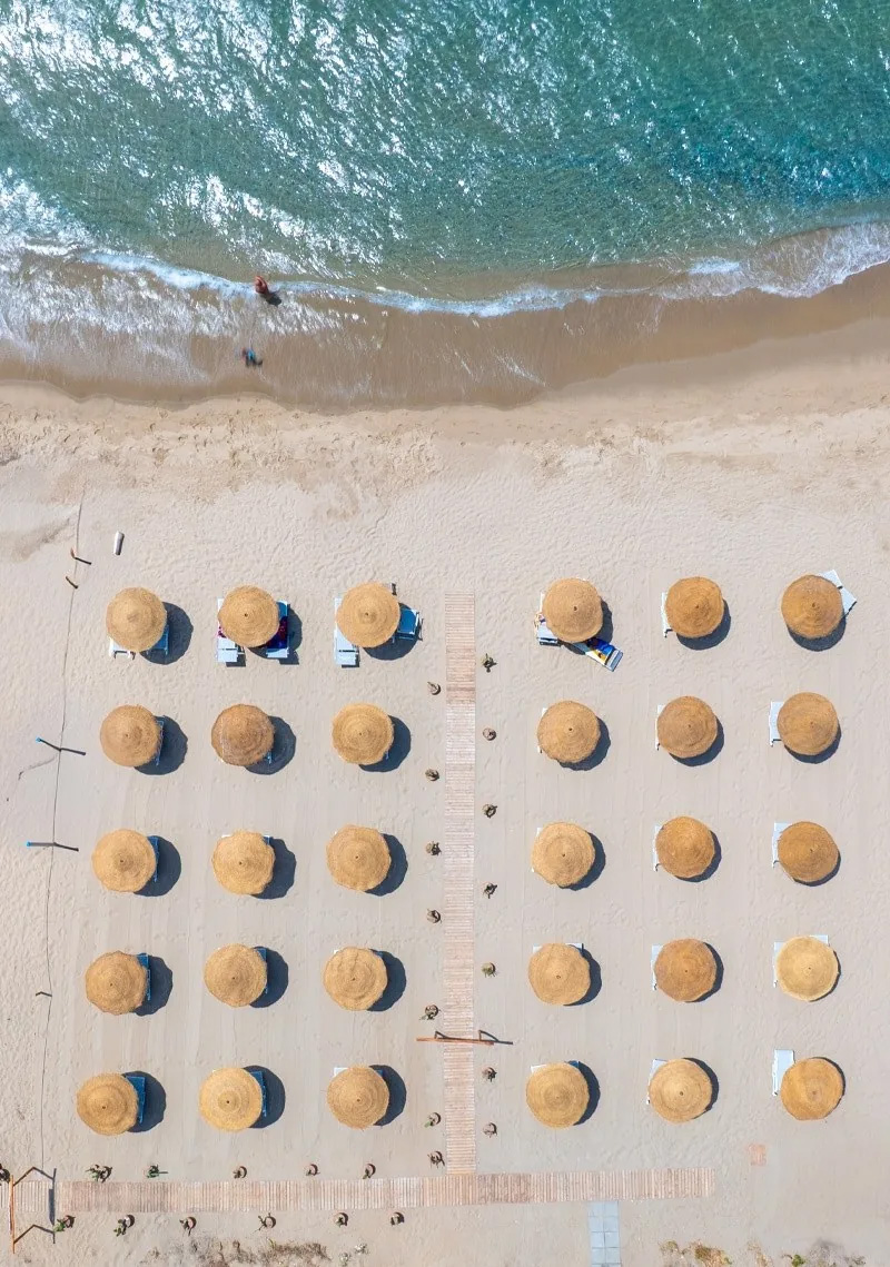Vista aerea degli 30 ombrelloni in paglia del Mediterraneo Beach Club – Caprioli di Pisciotta, Cilento